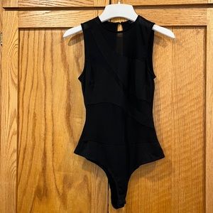 Black cutout body suit, high neck with cutouts on chest and abdomen.